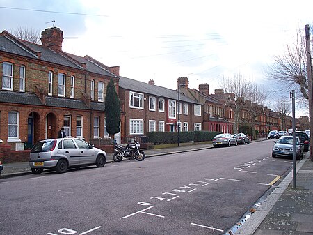 Three houses of an obviously 1950s rectilinear design are surrounded by typical Victorian Gothic houses.