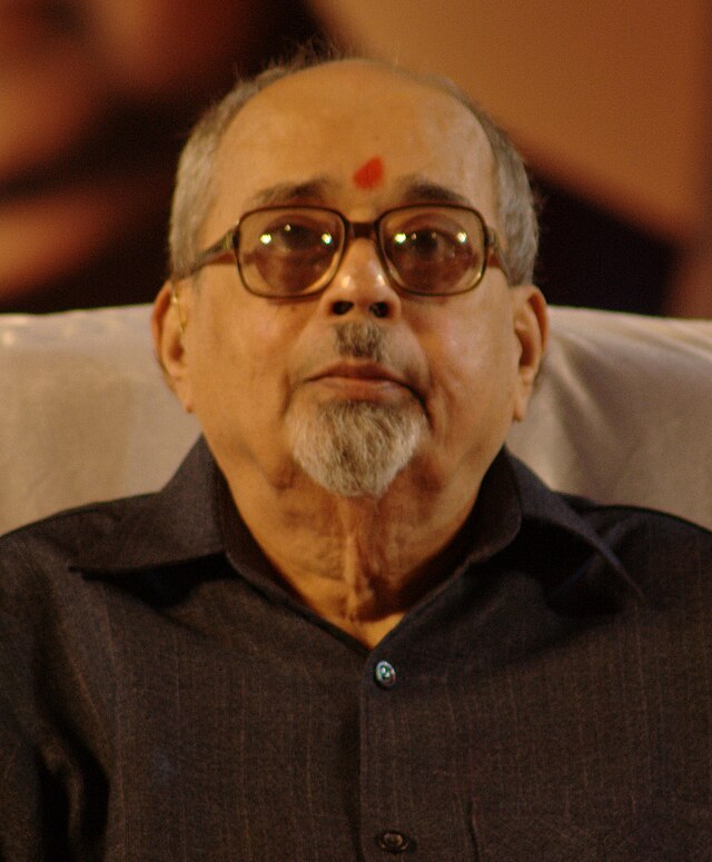 Photograph of an old man wearing black glasses.