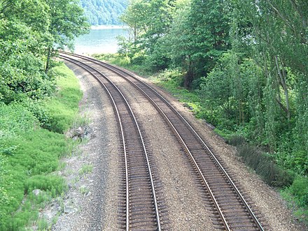 A double-track railway line running through a wooded area.
