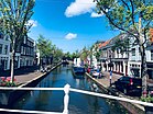 Photographie en couleurs d'un canal longé par des péniches à quais et d'un bâtiment en arrière-plan.