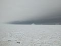 This picture shows the feature known as a water sky. In an overcast cloudy day sea ice is reflected white on the clouds - so the clouds appear light in color. In contrast the water is reflected as a dark color.