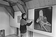 Conservator G. Groenewoud tijdens de inrichting van het museum, voor het schilderij 'De Steenkruiwagen van C. Adema', van 1977