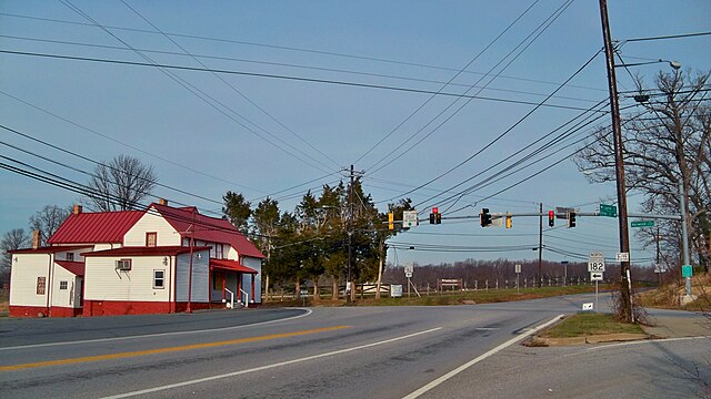 A photograph of a highway crossroads with a red and white wood historic building on the left