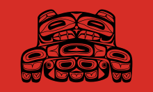 A red banner with a bear in the traditional Coast Salish-formline art style