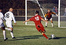 The striker (wearing the red shirt) is past the defence (in the white shirts) and is about to take a shot at the goal. Football in Bloomington, Indiana, 1996.jpg