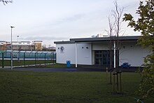 The Key Stage 2 entrance of the 2011 buildings of Gosforth Junior High Academy. A section of the 1930s buildings can still be seen in the middle-right. The Virgin Money banking headquarters can be seen in the background. Gosforth Junior High Academy Key Stage 2 Entrance.jpg