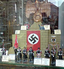Modern produced miniature figures of Nazi Party members and Nuremberg Rally propaganda items on sale in Carlisle, UK 2009. King & Country 1-30 scale collerctor's toy soldiers Nazi figures SS parade uniforms ceremonial mace flag-bearer Goering Reichsadler Eagle-and-swastika Nuremberg rally stand etc Window exhibition hobby shop Carlisle UK 2009.jpg