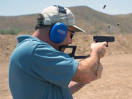 Man firing a fully automatic 9×19mm Glock 18 machine pistol with a shoulder stock