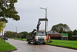 Here, this photographer is caught short waiting for the lamppost he was watching as workers lower the new Fabrikat post into place.