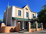 This stately double-storeyed house was erect by the immigrant Heinrich Wilhelm Becker in 1876. He was Mayor of Ladismith for an unbroken period of 32 years.
Type of site: House
Current use: Residential. This stately double-storeyed house was erect by the immigrant Heinrich Wilhelm Becker in 1876. He was Mayor of Ladismith for an unbroken period of 32 years. Oakdene, Ladismith.jpg