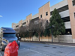 A parking garage with several evergreen trees in front of it