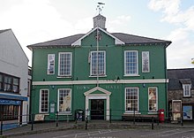 Photo de la façade d'un bâtiment à deux étages aux murs verts avec de grandes fenêtres rectangulaires