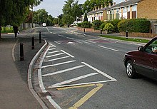 A curb extension marked by darkened tarmac and black posts Traffic calming.jpg