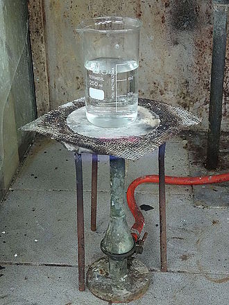 An asbestos heatproof mat over a Teclu burner A laboratory heat spreader made of asbestos, over Teclu burner.jpg