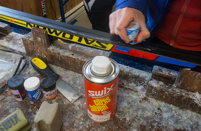 Application of grip wax to a classic cross-country ski, using a canister of wax, like those shown in the left foreground.