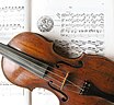 Das Foto zeigt den Ausschnitt einer Geige, die auf dem Notenblatt der Rosenkranz-Sonaten liegt.