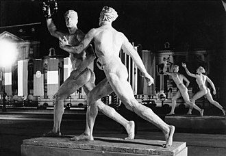 Statues representing the ideal body were erected in the streets of Berlin for the 1936 Summer Olympics. Bundesarchiv B 145 Bild-P017100, Berlin, Olympiade, Pariser Platz bei Nacht.jpg
