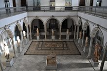 Salle de Carthage vue du deŭième étage avec les statues romaines et une mosaïque, ainsi que les arcades du palais.