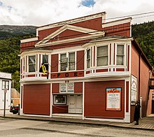 The Eagles Hall in 2017 featuring a costumed performer sticking her leg out the windowsill. She is attempting to attract passersby to watch the show. Centro historico de Skagway, Alaska, Estados Unidos, 2017-08-18, DD 42.jpg