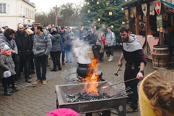 Blacksmith in Ribeauvillé working on a square shaped table with coal