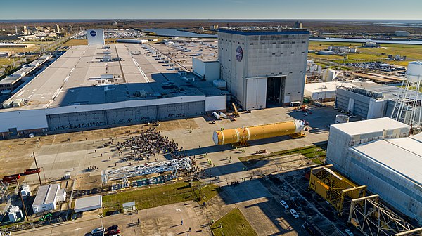 The Michoud main manufacturing building and the twin vertical assembly buildings as seen from a drone in January 2020. The Artemis 1 core stage is being rolled out, along with a crowd of workers