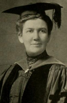 A white woman wearing academic mortarboard cap and gown