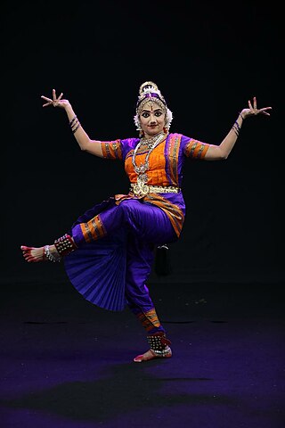 Bharatnatyam dancer in a saraswati pose during her performance on a dark  background. - SuperStock