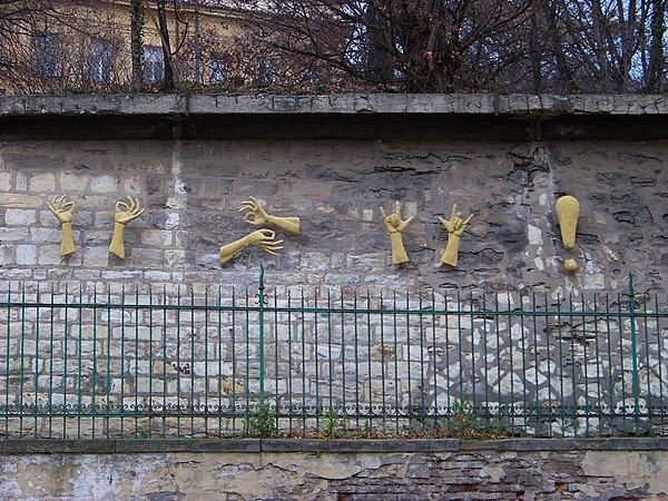 Sign language relief sculpture on a stone wall: "Life is beautiful, be happy and love each other", by Czech sculptor Zuzana Čížková on Holečkova Stree