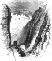 A black-and-white drawing of a steam train emerging from a tunnel