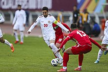 A Lebanese player dribbling past two Iranian defenders