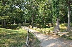 Parque con valla rústica, camino pequeño y colinas.