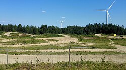 Kaksi tuulivoimalaa näkyy Muukon motocross-radan takana heinäkuussa 2018.