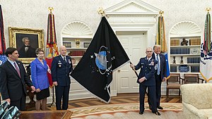 גנרל ג'יי ריימונד ורוג'ר טוברמן מציגים לנשיא ארצות הברית דונלד טראמפ את דגל חיל החלל החדש. מימין נשיא ארצות הברית לשעבר טראמפ ומשמאל מזכיר ההגנה של ארצות הברית, מארק אספר