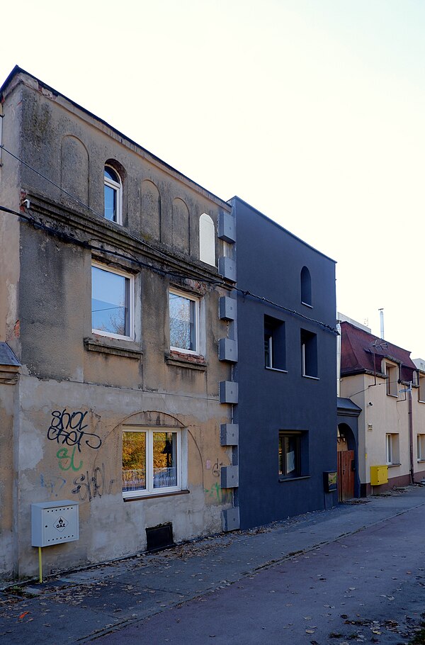 A semi-detached house with one half of the facade in the original state and the other half after insulation with polystyrene