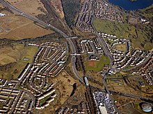 Aerial view of the M80 motorway looking east at Provanmill as it passes under the Cumbernauld Line railway tracks and the B765 Robroyston Road (2018) The M80 motorway from the air (geograph 5716335).jpg