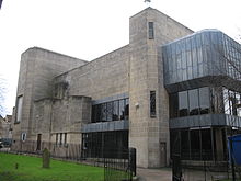 Concrete building with large glass windows.