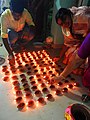 Women lighting earthen lamps on occasion of 2017 Sandhi puja at Manikanchan 31