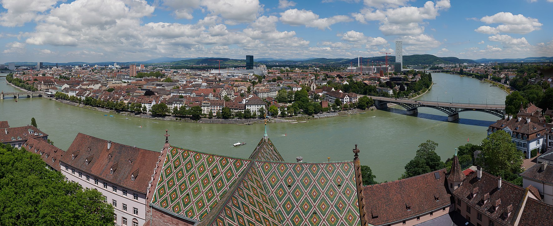 Blick vom Martinssturm des Basler Münsters auf Kleinbasel und das Rheinknie. Links am Rand ist die Mittlere Brücke zu erkennen, rechts sind Messeturm, Roche Tower und die Wettsteinbrücke zu erkennen.