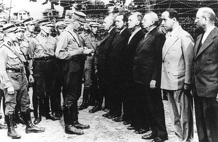 Des SA devant des membres prisonniers du SPD en août 1933 au camp de concentration d'Oranienbourg, de gauche à droite : Ernst Heilmann (en), Friedrich Ebert junior, Alfred Braun, Heinrich Giesecke, Hans Flesch (de) et Kurt Magnus.