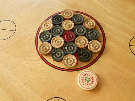 Carrom men and one striker, arranged at the start of a game