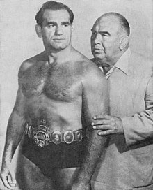 Longest reigning and Three-time champion Lou Thesz (wearing an early version of the belt) pictured with manager Ed Lewis in the 1950s Champion Lou Thesz and Manager Ed (Strangler) Lewis - Sports Facts - 21 April 1953 Minneapolis Armory Wrestling Program.jpg