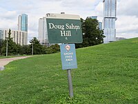 Firmar marcando Doug Sahm Hill con el edificio independiente visto en el fondo