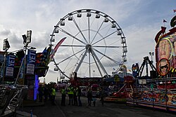 Hull Fair event staff milling about near one of three big wheels at the 2023 instalment of Hull Fair.