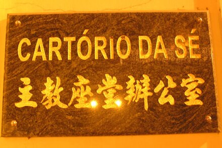 A sign in both Chinese and Portuguese in Macau - "主教座堂辦公室" (in Chinese) and "Cartório da Sé" (in Portuguese), which means "Office of the Cathedral."