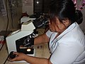 Nurse examining cells to test for malaria (10711223926).jpg