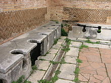 Photographie de toilettes publiques romaines (latrines), dans le port antique d'Ostie.