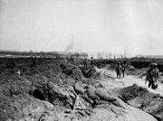 Soldiers march along a sunken dirt road in small groups