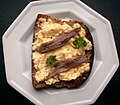 Scotch Woodcock. A traditional Scottish food made with creamy scrambled eggs on toast spread with anchovy paste. This portion is garnished with parsley and anchovy fillets.