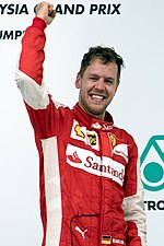 A picture of Sebastian Vettel cheering on the podium after winning the 2015 Malaysian Grand Prix for Ferrari.