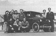 東京電気自動車（株）の最初の生産車たまEOT-47と共に、田中次郎（最前列右端）、日村卓也（車の背後、右から二人目）、そして同社の設計課全員、同社府中工場にて。（なお、日村卓也は、桜井眞一郎の、たま自動車～プリンス自動車工業における最初の直属上司である。）
